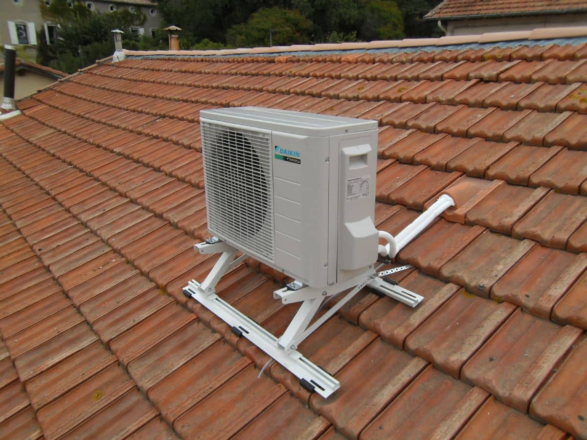 Groupe extérieur de climatisation posé sur châssis en toiture de tuiles à Bordeaux